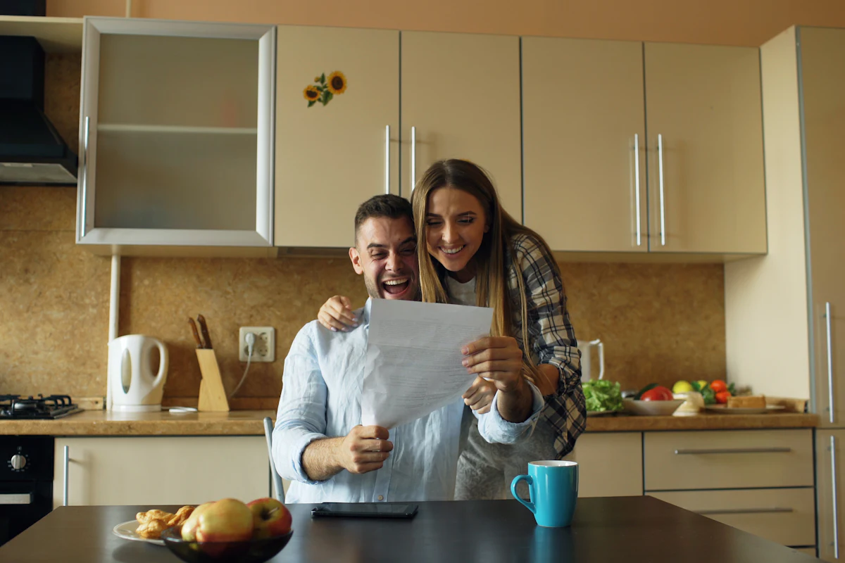 Couple smiling while reading a letter together in their kitchen